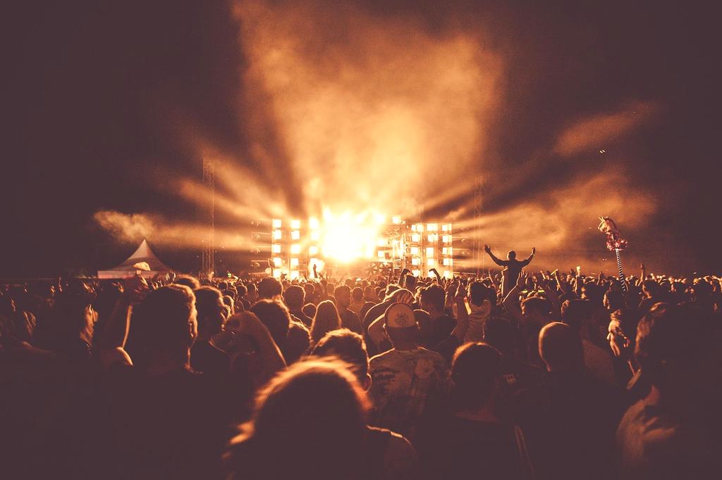 Audience hands raised in front of bright stage lighting